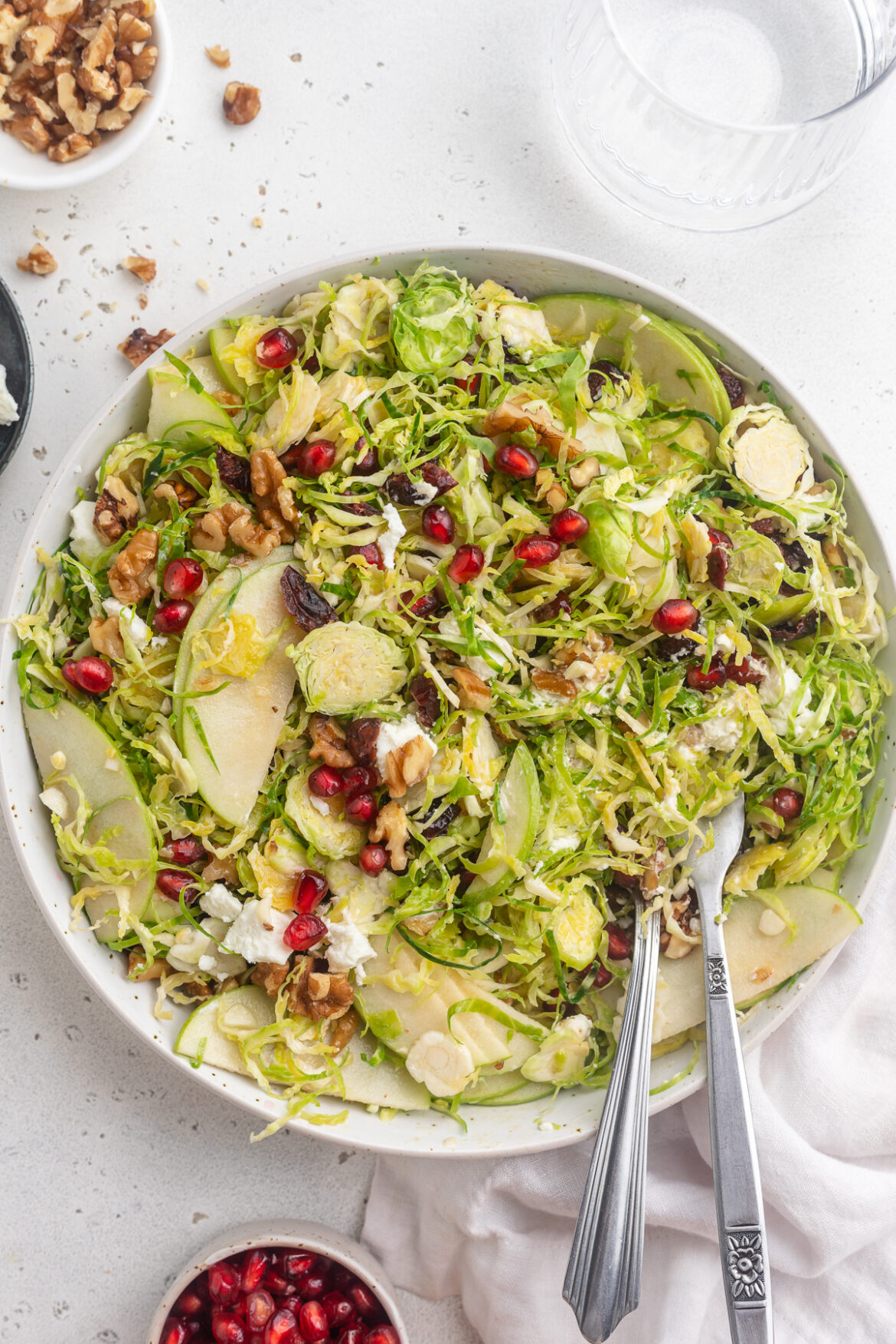 Brussels Sprout Salad overhead image of brussels sprout salad with walnuts and pomegranate seeds on the side.
