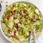 overhead image of brussels sprout salad with walnuts and pomegranate seeds on the side.