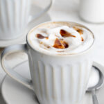 healthy caramel brulée latte in a mug with a spoon on the side.