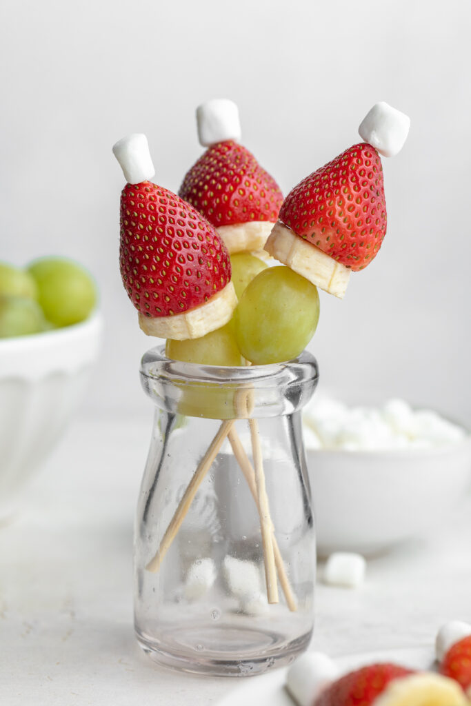 grinch fruit kabobs in a glass, standing upright.