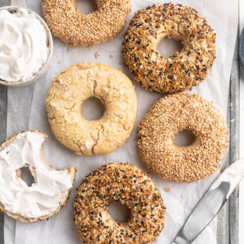 gluten-free bagels on a baking sheet with cream cheese on the side.