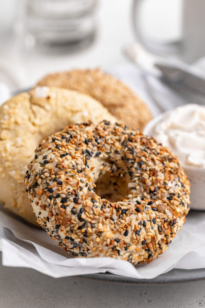 gluten-free bagels on a plate with cream cheese on the side.