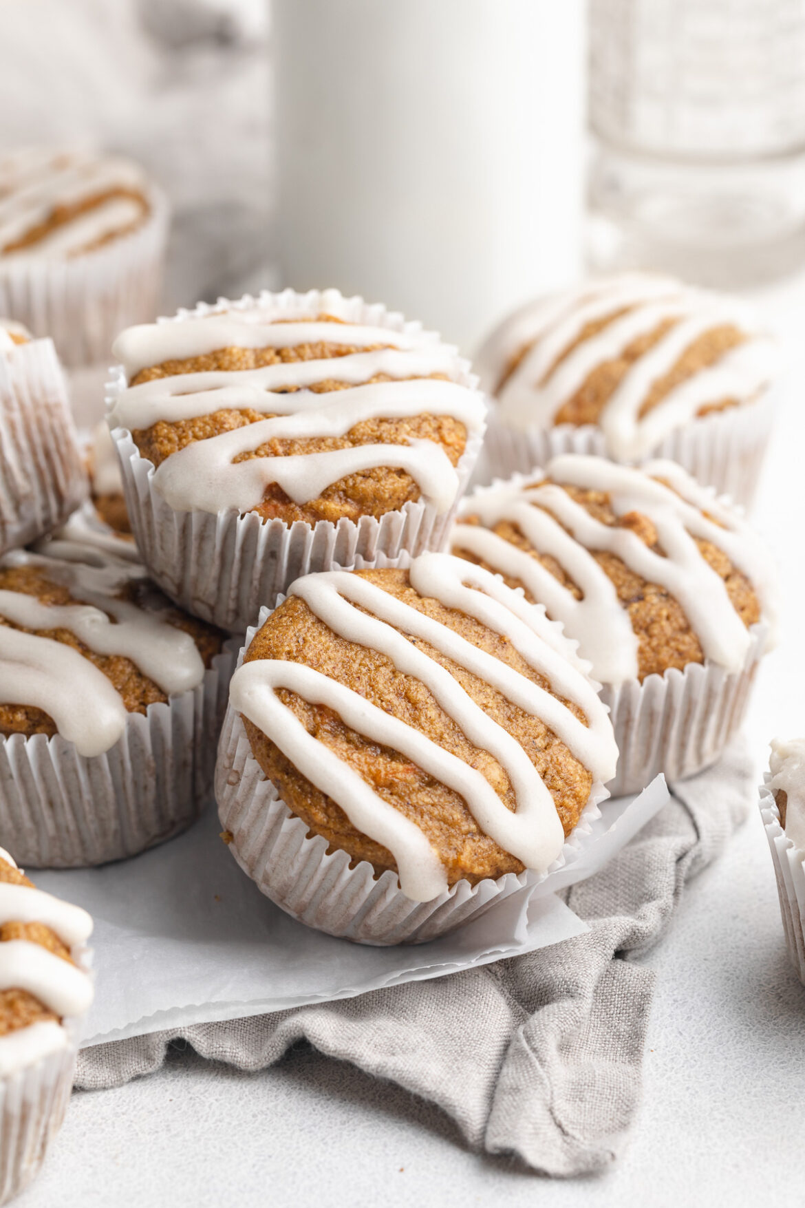 Healthy Carrot Cake Muffins with Cream Cheese Icing healthy carrot cake muffins with cream cheese icing on top, stacked on top of each other.