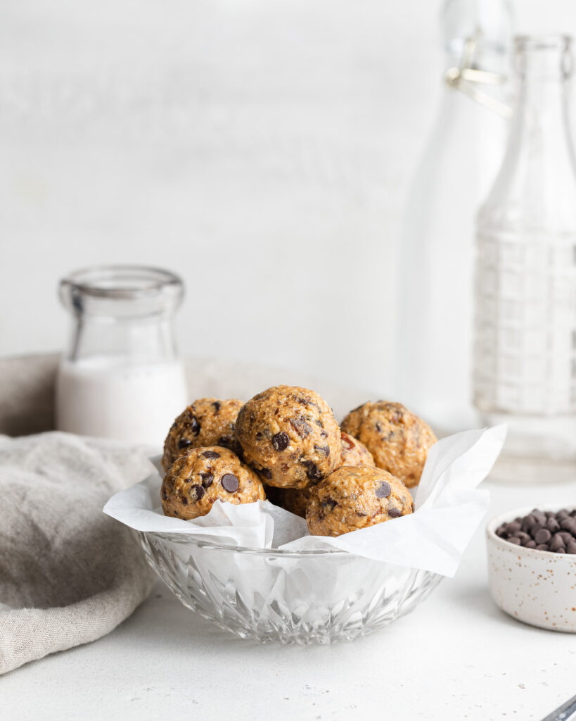 Cookie dough date bites in a bowl with milk and chocolate chips on the side.
