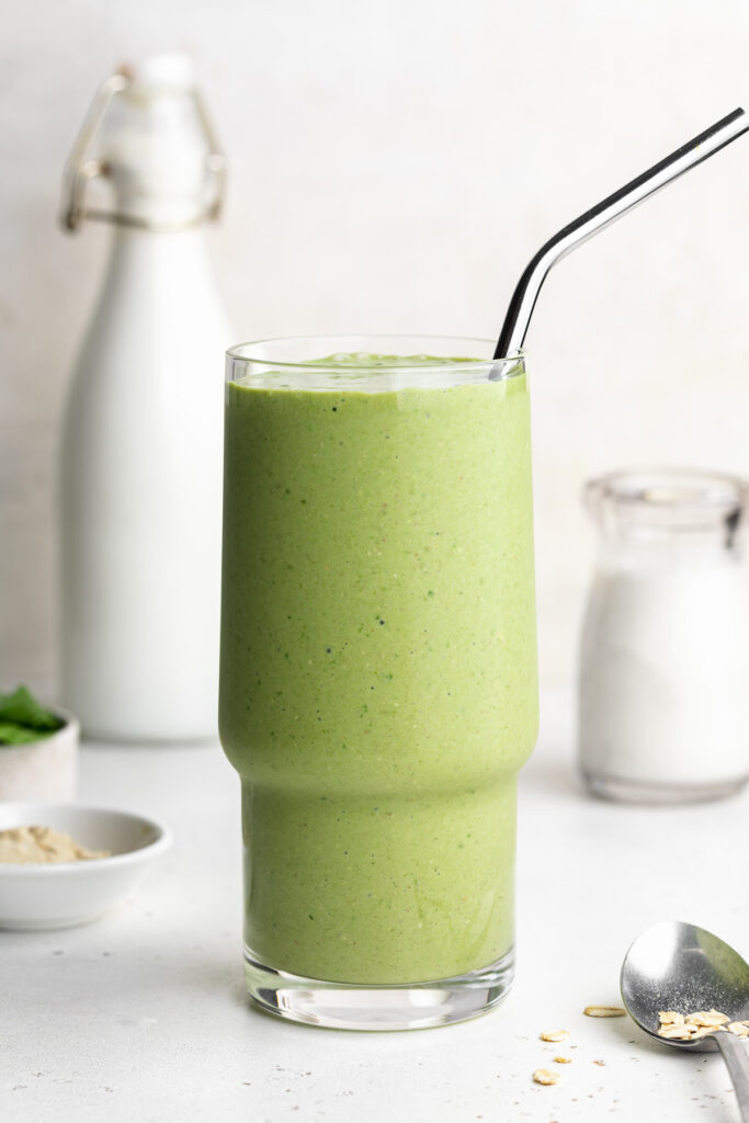Nourishing green lactation smoothie with a metal straw.