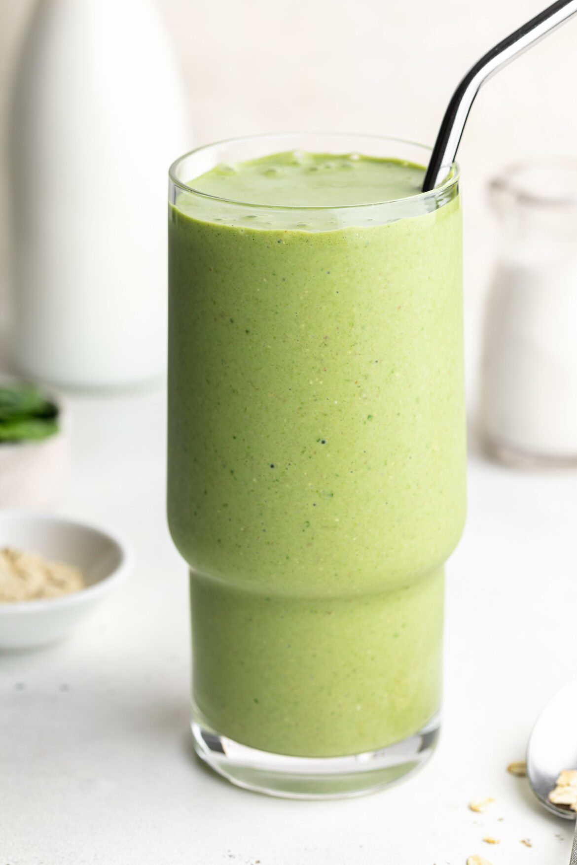 Nourishing Green Lactation Smoothie close-up image of a nourishing green lactation smoothie with a metal straw.
