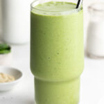 close-up image of a nourishing green lactation smoothie with a metal straw.