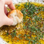 bread being dipped into garlic and herb olive oil dip.