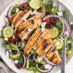 overhead image of mediterranean grilled chicken salad in a bowl with fresh mint on the side.
