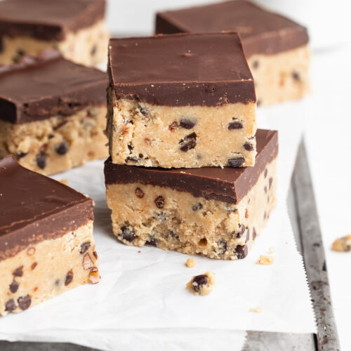 two healthy no-bake cookie dough bars stacked on top of each other on a baking sheet.