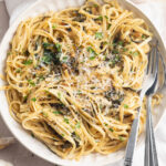 close-up overhead image of pasta with caramelized zucchini in a bowl with parsley and parmesan cheese on top.
