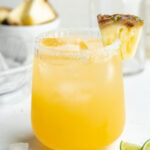 Pineapple margarita in a glass with a pineapple slice on the side.