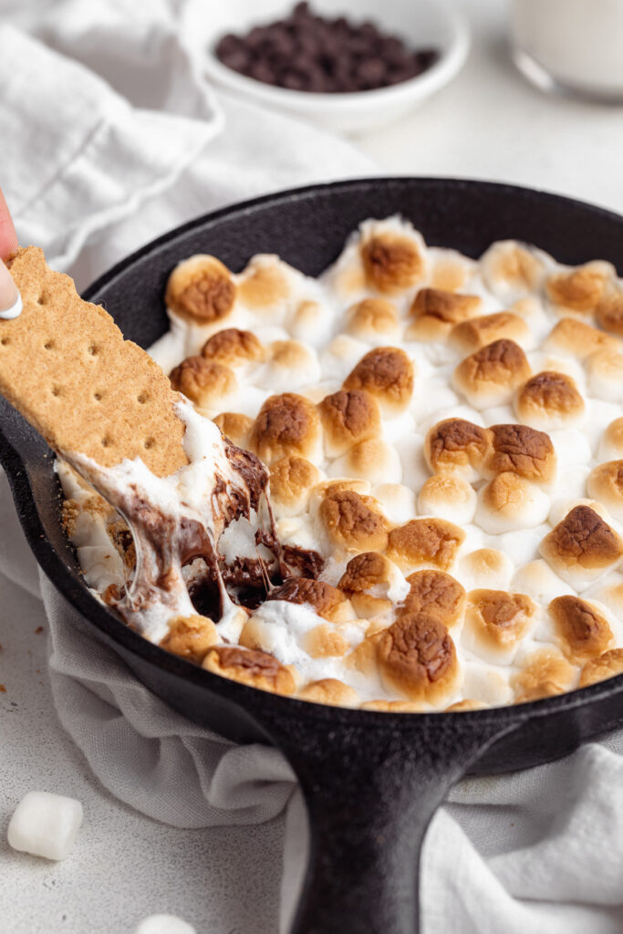 graham cracker being dipped into s'mores dip