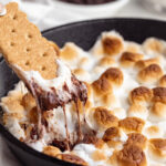 graham cracker being dipped into s'more dip
