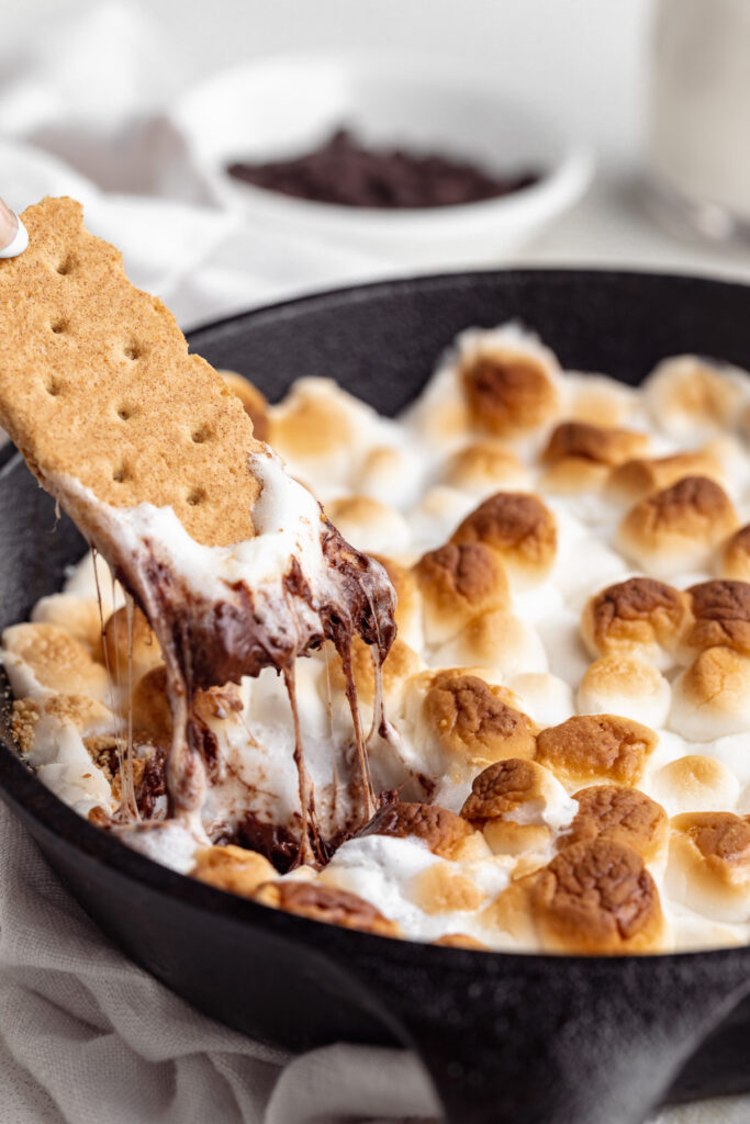 graham cracker being dipped into s'more dip
