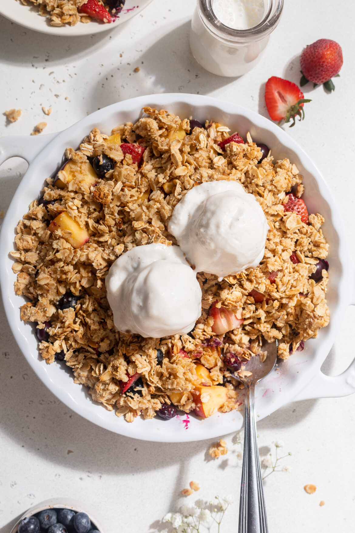 Healthy Summer Fruit Crisp Overhead image of summer fruit crisp in a baking dish with vanilla ice cream on top.