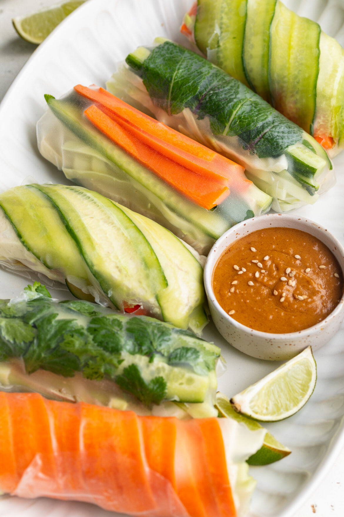 Summer Rolls with Peanut Dipping Sauce summer rolls on a serving platter with peanut dipping sauce and a fresh lime on the side.