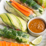 summer rolls on a serving platter with peanut dipping sauce and a fresh lime on the side.