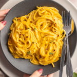 Placing down a bowl of vegan creamy butternut squash pasta.