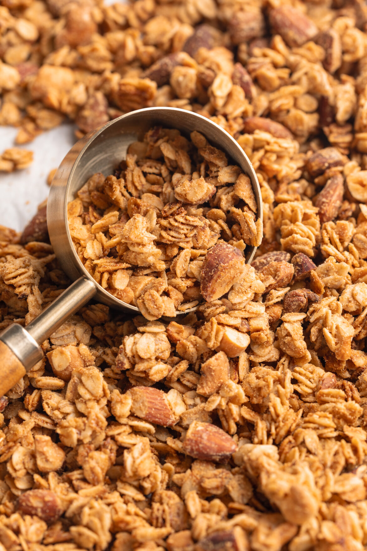 5-Ingredient Healthy Homemade Granola Recipe Homemade granola being scooped off a baking sheet with a measuring scoop.