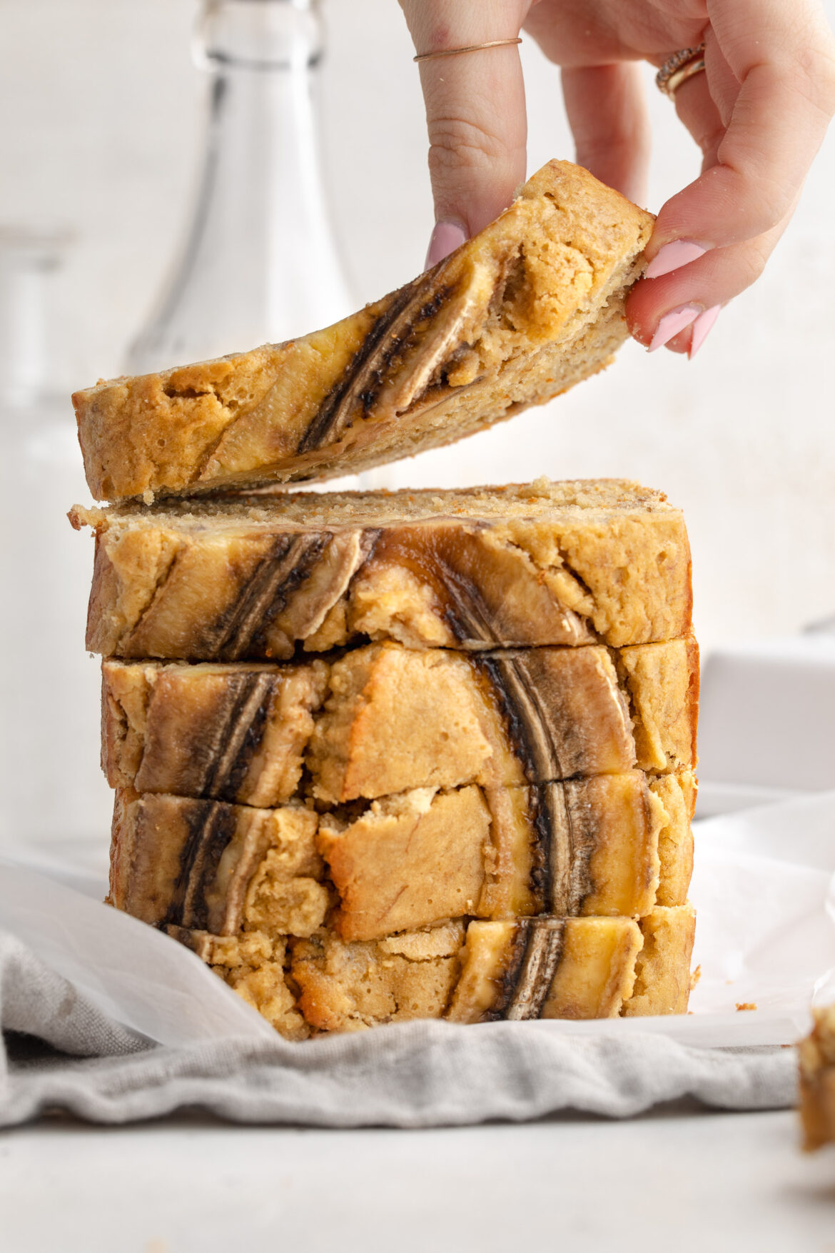 4-Ingredient Banana Bread (gluten-free!) Stacked slices of 4 ingredient banana bread, with a hand lifting the top slice.