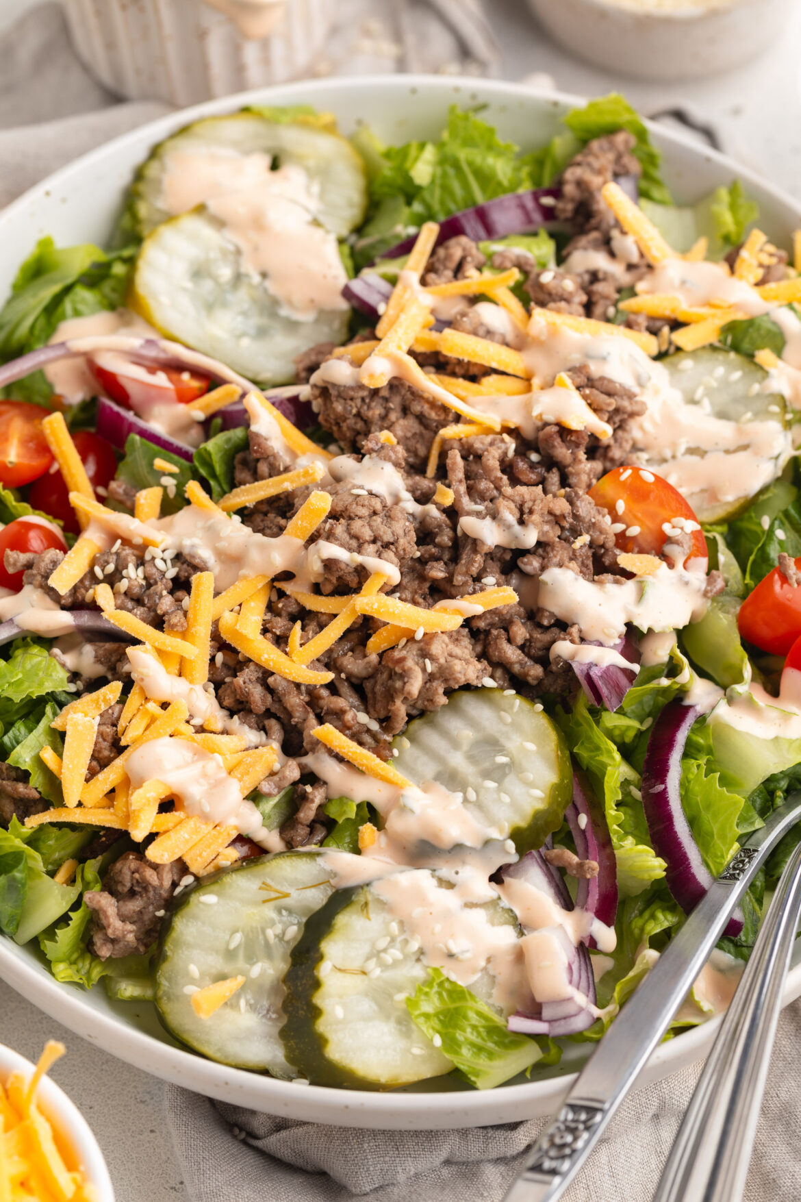 Healthy Big Mac Salad big mac salad in a bowl with sesame seeds on top.