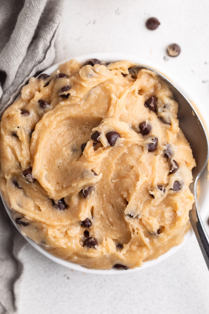 overhead image of gluten free edible cookie dough in a small dish with a spoon.