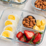 Back to basics high protein snack box with fresh strawberries, boiled eggs, cheese, and almonds.
