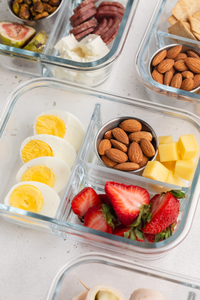 Back to basics high protein snack box with fresh strawberries, boiled eggs, cheese, and almonds.