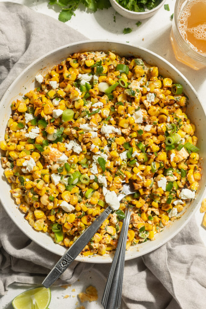 overhead image of Mexican street corn salad in a large serving dish with fresh cilantro on the side.