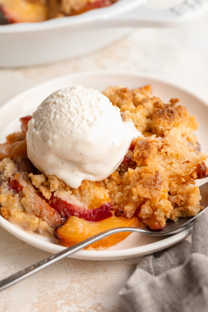4 ingredient peach cobbler on a plate with ice cream on top.