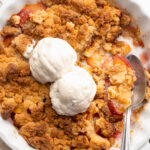 overhead image of 4 ingredient peach cobbler in a baking dish with ice cream on top.