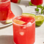 watermelon paloma in a glass with a lime slice and a small slice of watermelon.