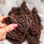 holding a piece of brownie batter bark
