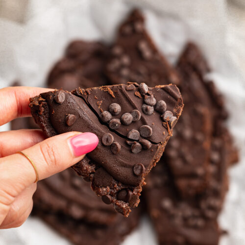 holding a piece of brownie batter bark