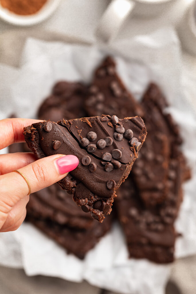 holding a piece of brownie batter bark
