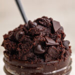 close up image of healthy edible brownie batter in a jar with a spoon.
