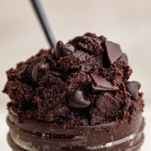 close up image of healthy edible brownie batter in a jar with a spoon.