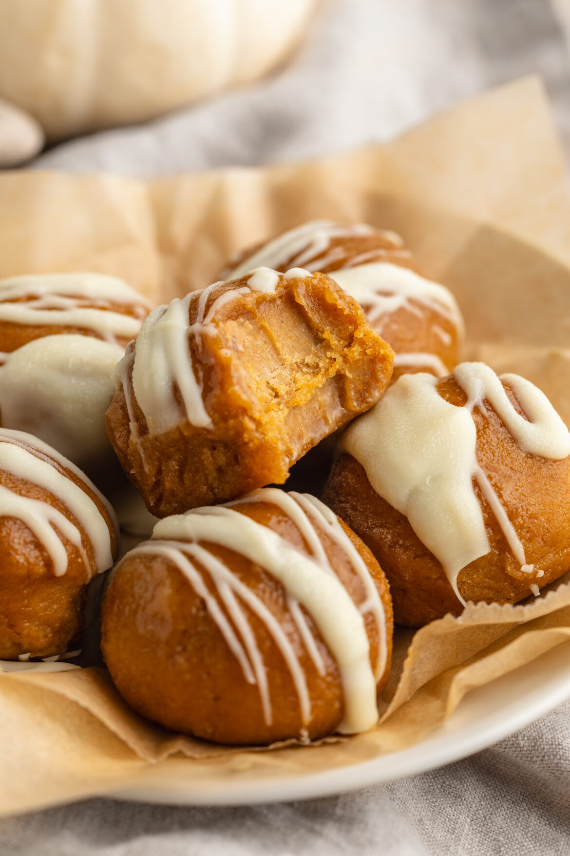 Pumpkin Protein Balls (gluten-free & dairy-free!) pumpkin protein balls on a plate with white chocolate drizzled on top.