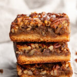 three healthy gluten free pecan pie bars stacked on top of each other.