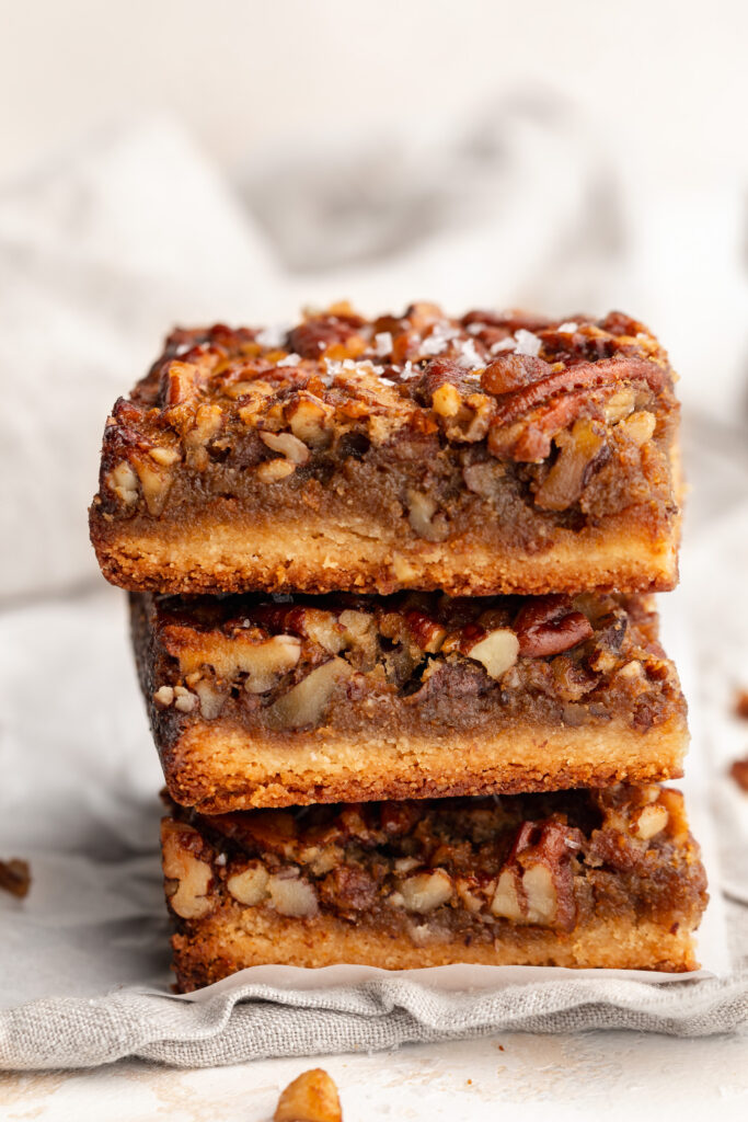three healthy gluten free pecan pie bars stacked on top of each other.