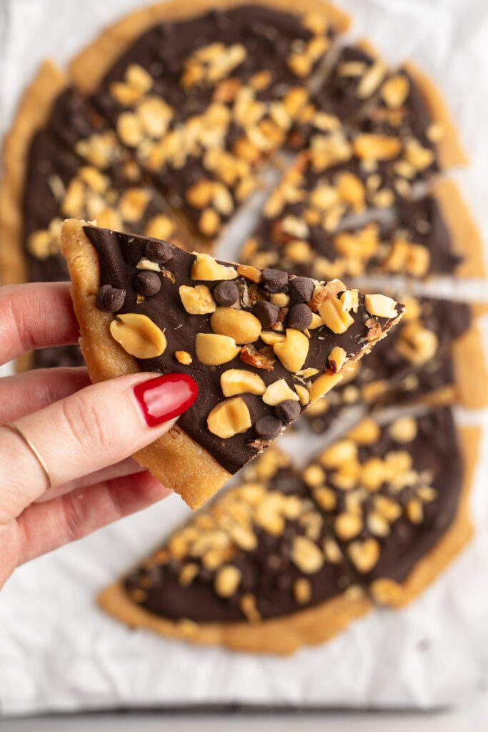 Hand holding a piece of 4 ingredient peanut butter cup cookie dough bark.