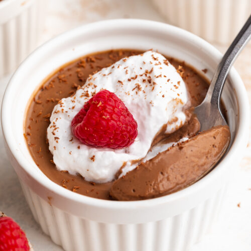 silken tofu chocolate mousse in a small ramekin with whipped cream and a raspberry on top.