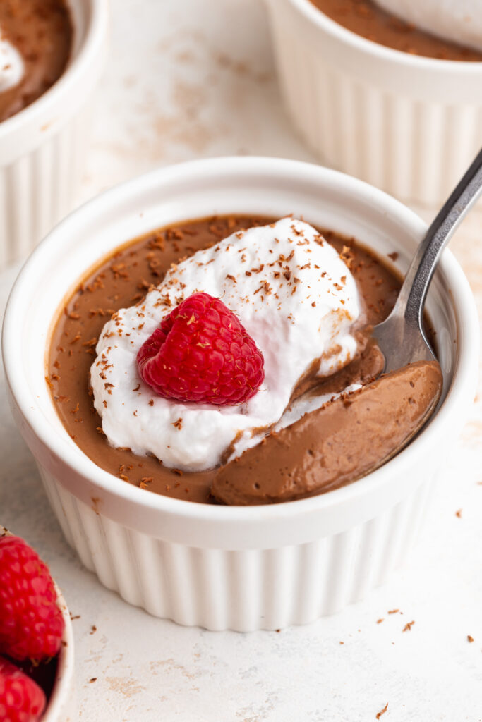 silken tofu chocolate mousse in a small ramekin with whipped cream and a raspberry on top.