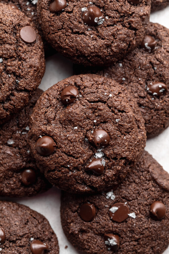 almond flour chocolate cookies on top of each other of a baking sheet.