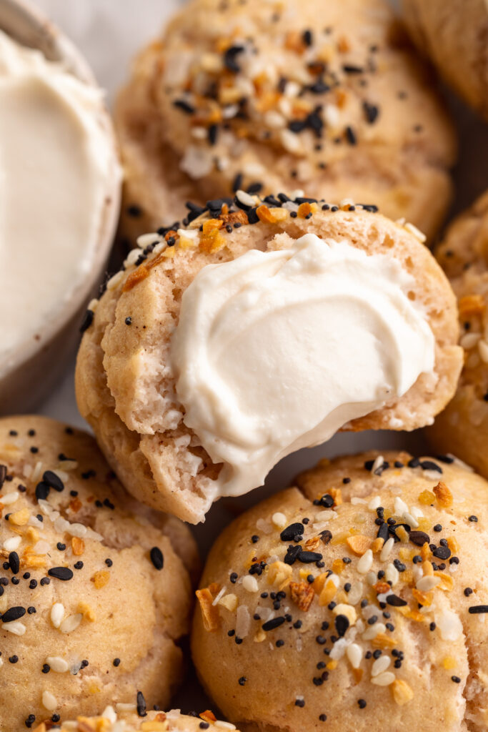 Close up image of a gluten-free bagel bite with everything bagel seasoning and cream cheese.