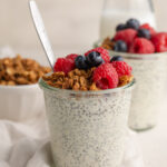 chia seed protein pudding in a glass jar with fresh blueberries and homemade granola on top.