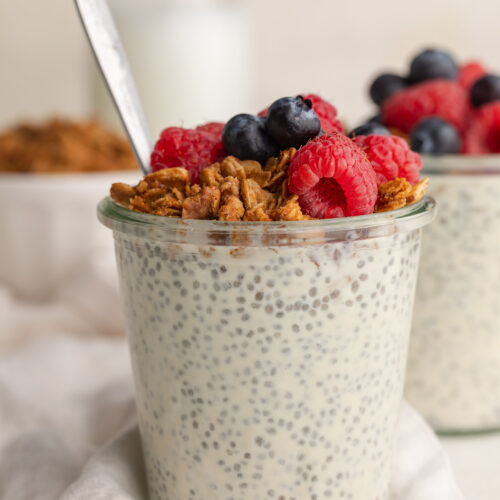 close up image of chia seed protein pudding in a jar with granola and fresh berries on top.