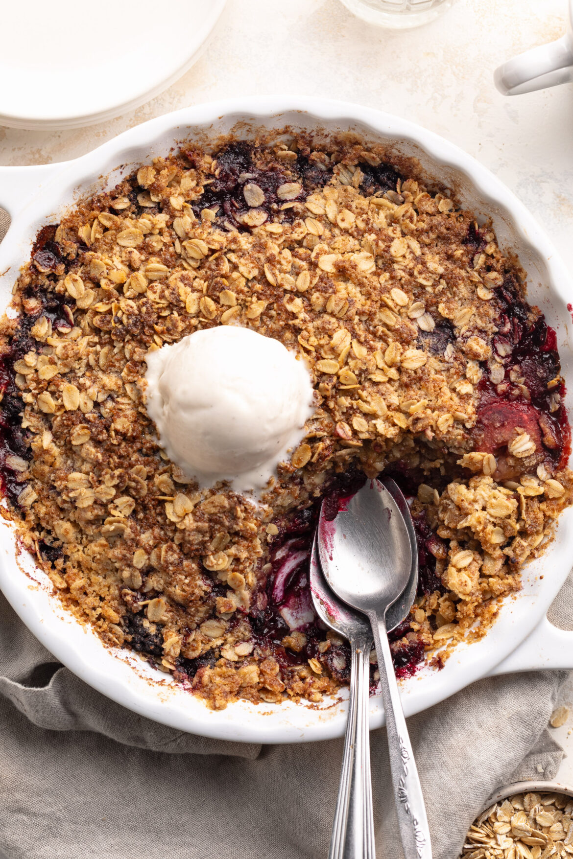 5-Ingredient Triple Berry Crisp with Frozen Berries Overhead image of triple berry crisp with frozen berries in a baking dish with a scoop of vanilla ice cream on top.
