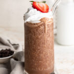 healthy milkshake in a glass with whipped cream and a strawberry on top.